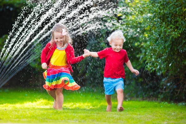 Crianças brincando com aspersor de jardim — Fotografia de Stock