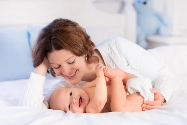 Mãe e bebê em uma cama branca — Fotografia de Stock