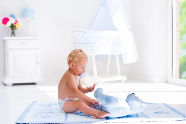 Junge mit Milchflasche im sonnigen Kinderzimmer — Stockfoto