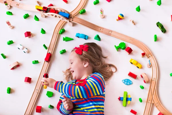 Menina brincando com trens de madeira — Fotografia de Stock