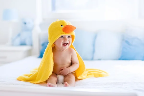 Симпатичный ребенок после ванны в желтом полотенце с уткой — стоковое фото