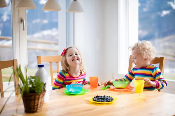 Barn som spiser frokost på solrikt kjøkken – stockfoto