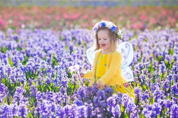 Liten flicka i fairy kostym spela blomma fältet — Stockfoto