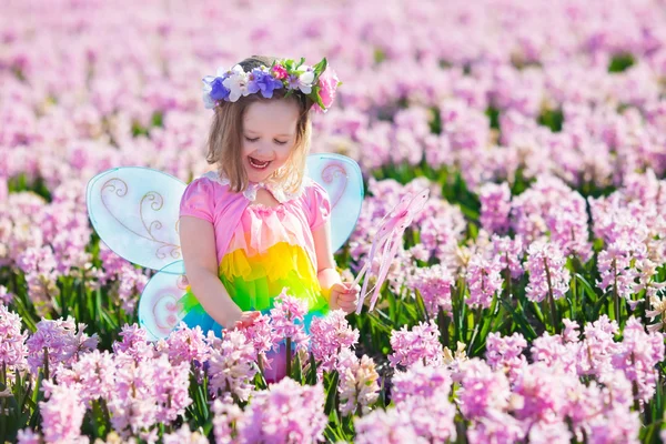 Klein meisje in fee kostuum op bloem gebied spelen — Stockfoto