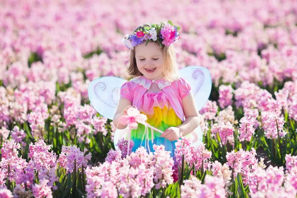 Menina em fantasia de fada jogando no campo de flores — Fotografia de Stock