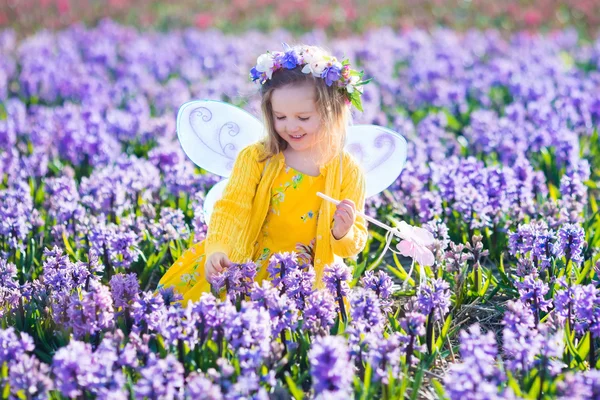 Menina em fantasia de fada jogando no campo de flores — Fotografia de Stock