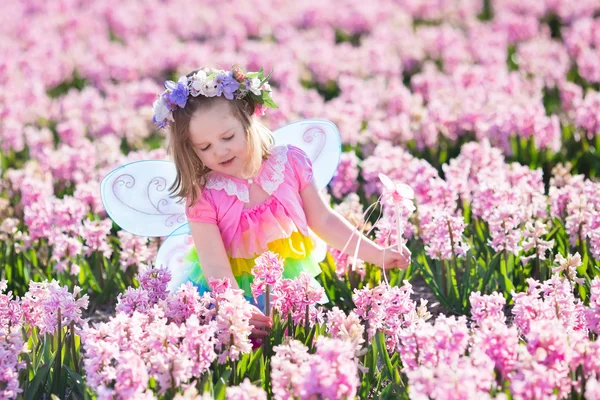Klein meisje in fee kostuum op bloem gebied spelen — Stockfoto