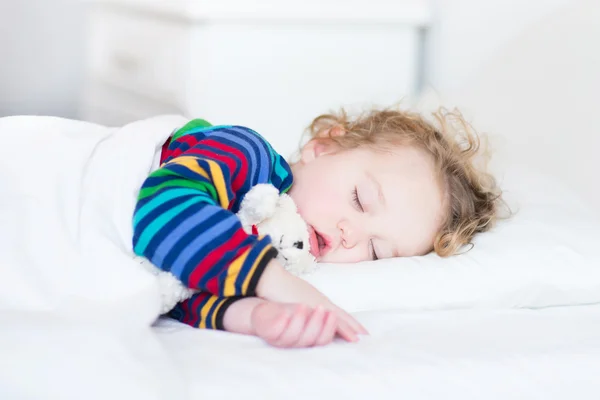 Bedårande barn girl tar en tupplur i en vit säng — Stockfoto