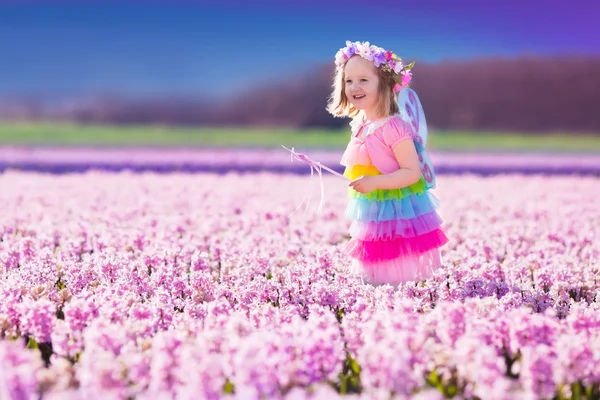 Liten flicka i fairy kostym spela blomma fältet — Stockfoto