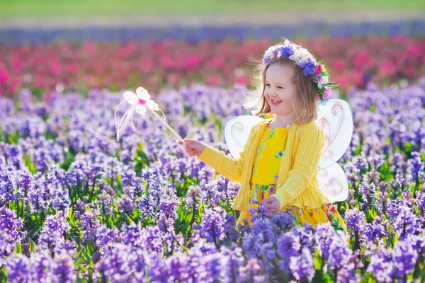 Menina em fantasia de fada jogando no campo de flores — Fotografia de Stock