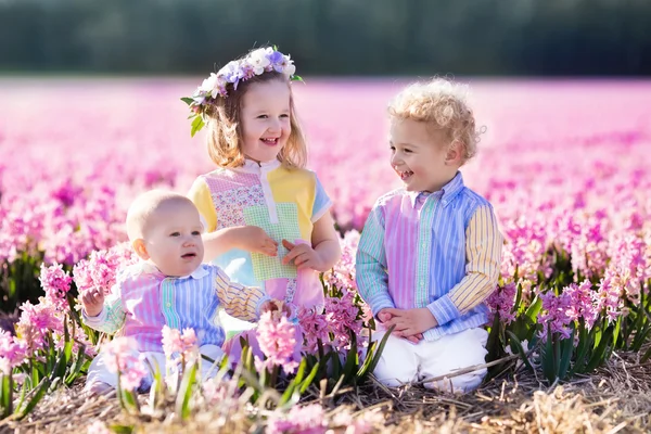 Drie kinderen spelen in prachtige hyacinten bloem veld. — Stockfoto