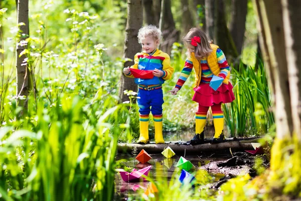 Kinderen spelen met kleurrijke papieren boten in een park — Stockfoto