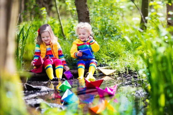 Kinderen spelen met kleurrijke papieren boten in een park — Stockfoto