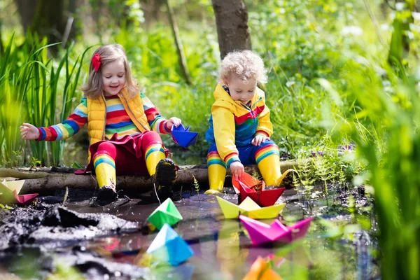 Crianças brincando com barcos de papel coloridos em um parque — Fotografia de Stock