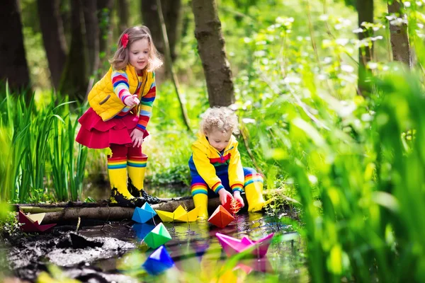 Kids playing with colorful paper boats in a park — Stock Photo, Image