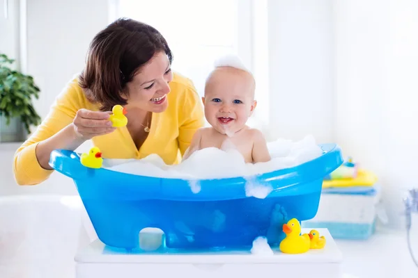 Young mother bathing baby boy