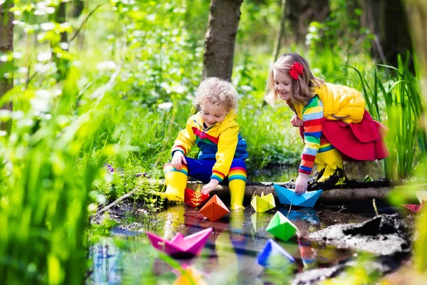 Kids playing with colorful paper boats in a park — Stock Photo, Image
