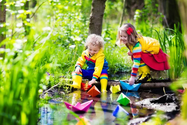 Barn som leker med färgglada papper båtar i en park — Stockfoto