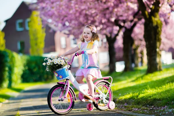 Little girl riding a bike on sunny spring day — Stockfoto