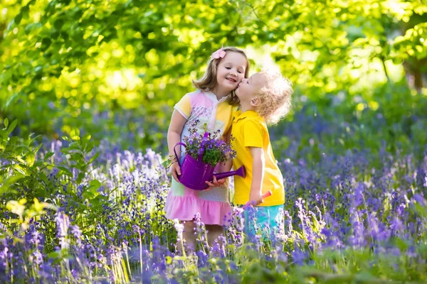 Niños jugando en el jardín floreciente con flores de Bluebell —  Fotos de Stock