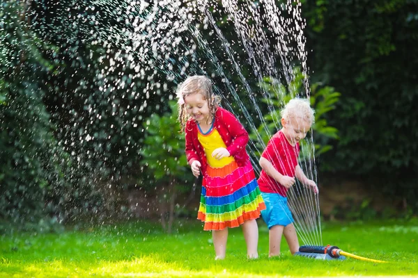 Děti hrají s zahradní postřikovače — Stock fotografie