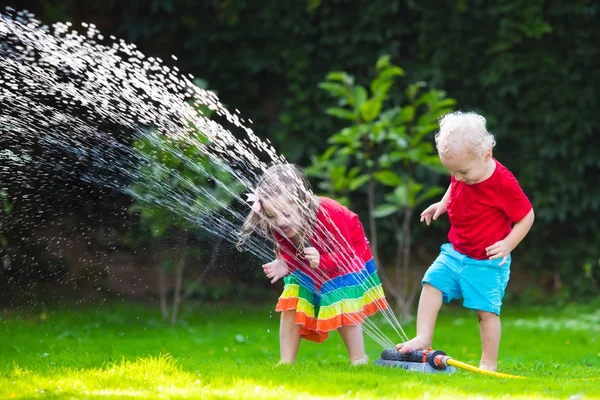 Niños jugando con aspersor de jardín — Foto de Stock