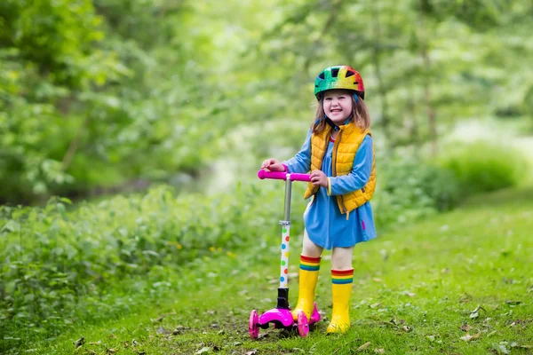 Menina montando uma scooter colorido — Fotografia de Stock
