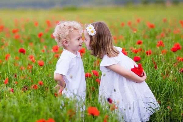 Crianças brincando no campo de flores de papoula vermelha — Fotografia de Stock