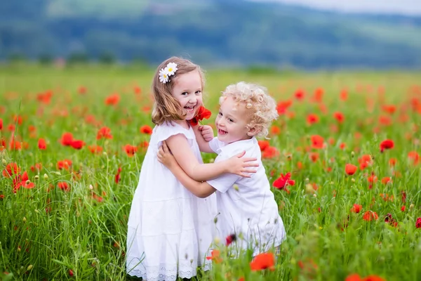 Діти грають у червоному маковому квітковому полі — стокове фото