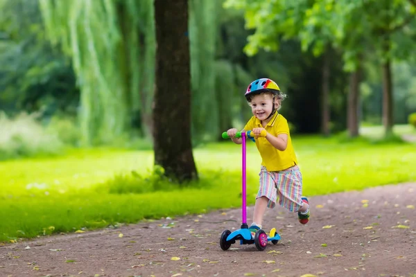 Mały chłopiec jedzie kolorowy skuter — Zdjęcie stockowe