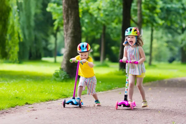 Little kids riding colorful scooters — Stock Photo, Image