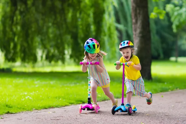 Små barn rida färgglada skotrar — Stockfoto