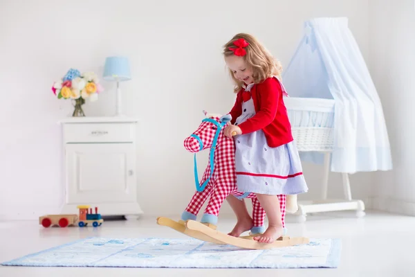 Menina montando um cavalo de brinquedo — Fotografia de Stock