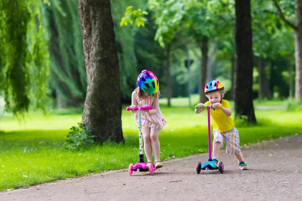 Kleine kinderen rijden kleurrijke scooters — Stockfoto