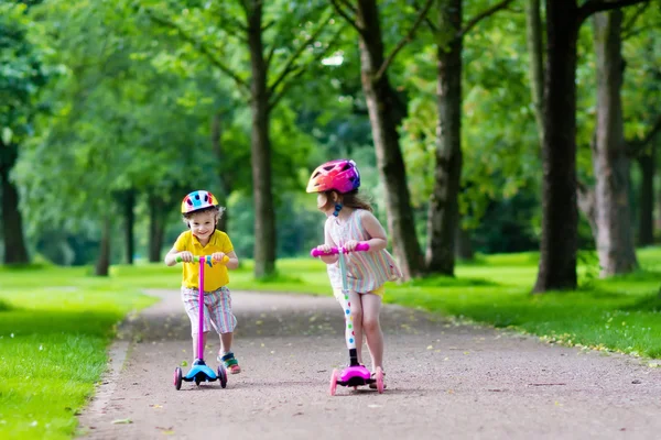 Kleine kinderen rijden kleurrijke scooters — Stockfoto