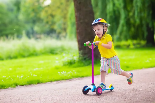 Niño montando un scooter colorido —  Fotos de Stock