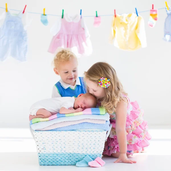 Broer en zus kussen pasgeboren baby — Stockfoto
