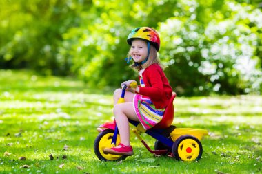 Little girl riding a tricycle clipart