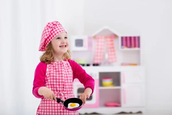 Menina brincando com cozinha de brinquedo — Fotografia de Stock