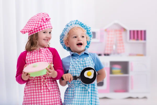 Діти грають з іграшковою кухнею — стокове фото