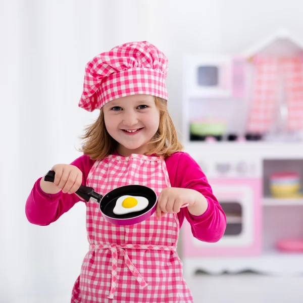 Menina brincando com cozinha de brinquedo — Fotografia de Stock