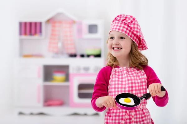 Menina brincando com cozinha de brinquedo — Fotografia de Stock