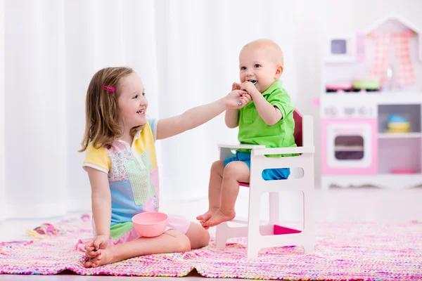 Little girl feeding baby brother — Stock Photo, Image