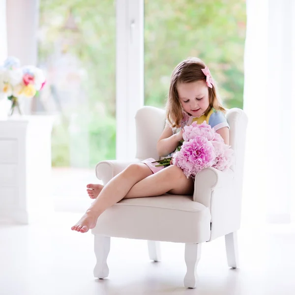 Bambina con fiori di peonia in camera da letto bianca — Foto Stock
