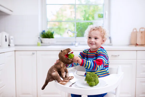 Petit garçon nourrir brocoli jouet dinosaure — Photo