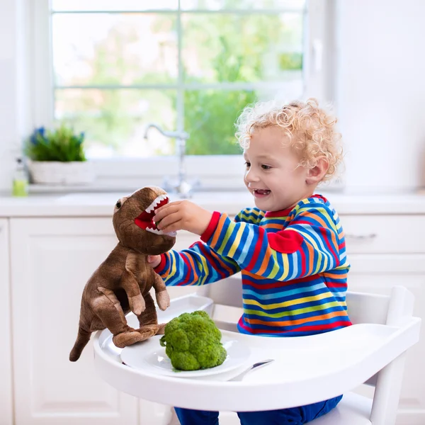 Petit garçon nourrir brocoli jouet dinosaure — Photo