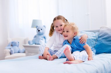 Beyaz yatak odasında oynayan çocuklar