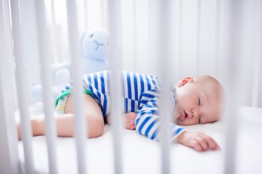 Sleeping baby boy in white crib clipart