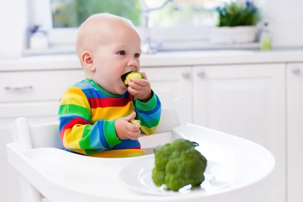 Liten gutt som spiser brokkoli på hvitt kjøkken – stockfoto