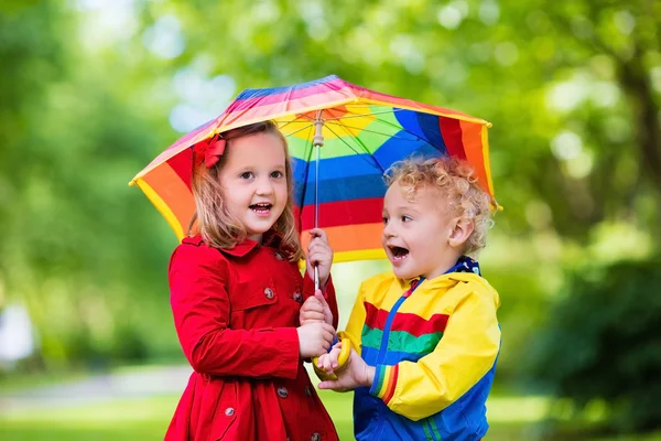 Renkli şemsiyesi altında yağmurda oynayan çocuklar — Stok fotoğraf
